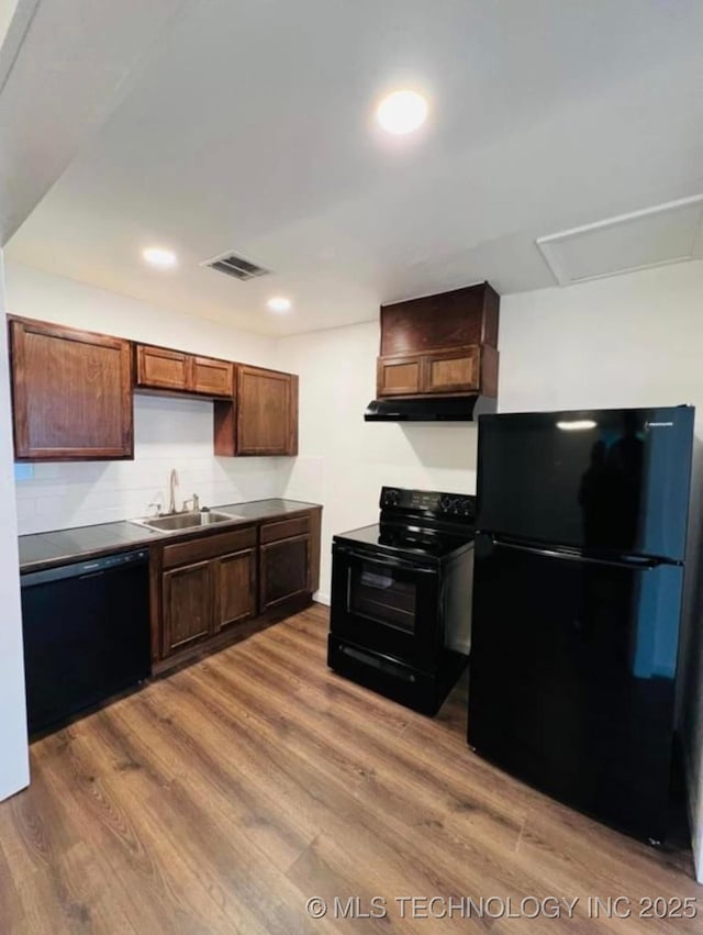 kitchen with visible vents, a sink, wood finished floors, under cabinet range hood, and black appliances