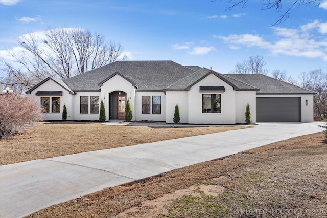 modern inspired farmhouse featuring stucco siding, roof with shingles, concrete driveway, and an attached garage