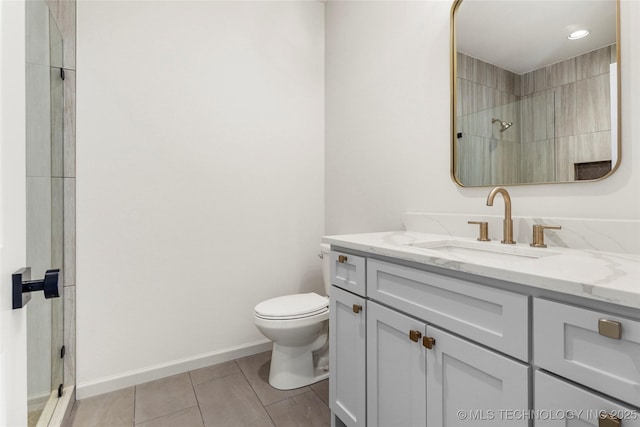 bathroom with tile patterned flooring, baseboards, toilet, a shower with shower door, and vanity