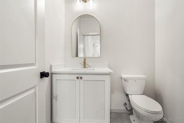 half bathroom with baseboards, toilet, and vanity