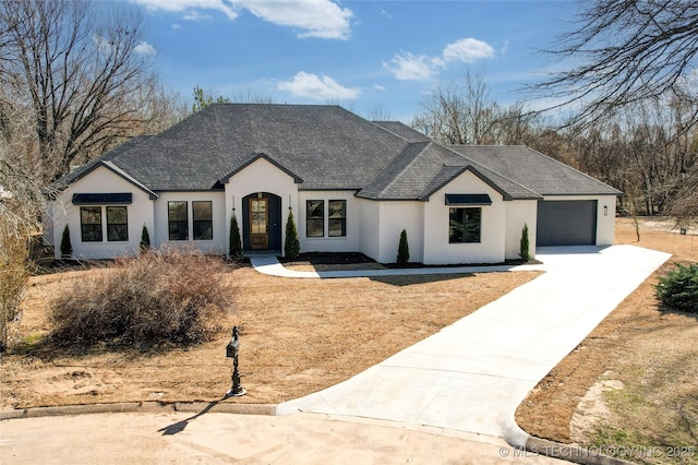 view of front of home featuring stucco siding, a garage, driveway, and roof with shingles