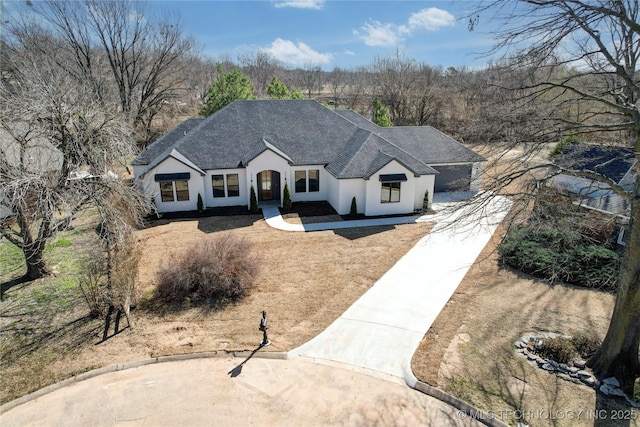 view of front of home featuring stucco siding, roof with shingles, and driveway