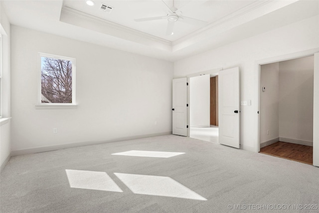 unfurnished bedroom with visible vents, carpet floors, a tray ceiling, and ornamental molding