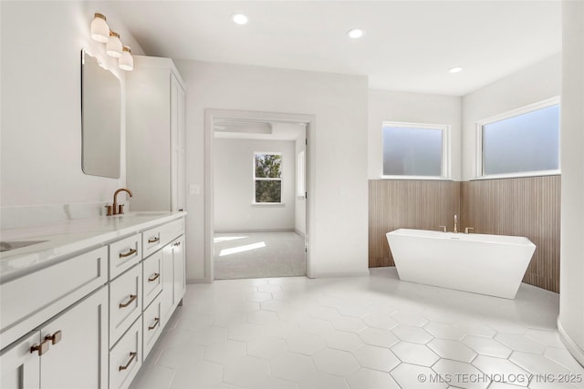 full bath with double vanity, a soaking tub, recessed lighting, a sink, and tile patterned flooring