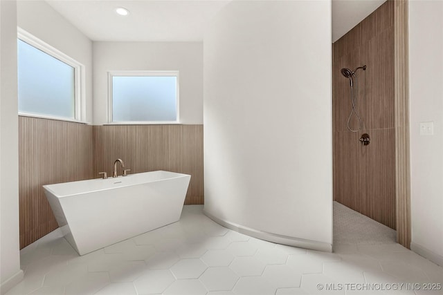 bathroom featuring wooden walls, a freestanding bath, a shower, wainscoting, and tile patterned floors