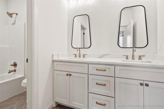 bathroom with double vanity, toilet, shower / bathing tub combination, and a sink