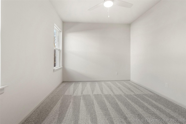 carpeted spare room featuring baseboards and ceiling fan