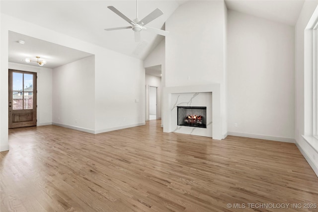 unfurnished living room featuring light wood finished floors, baseboards, and a premium fireplace