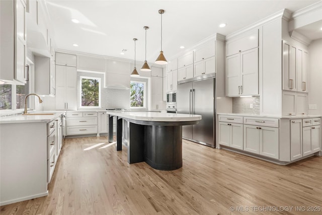 kitchen featuring white cabinetry, light countertops, built in appliances, and a sink