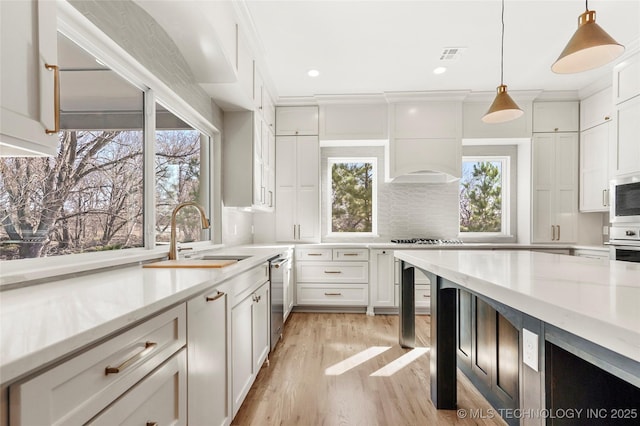 kitchen featuring visible vents, light wood-style flooring, a sink, white cabinets, and custom exhaust hood