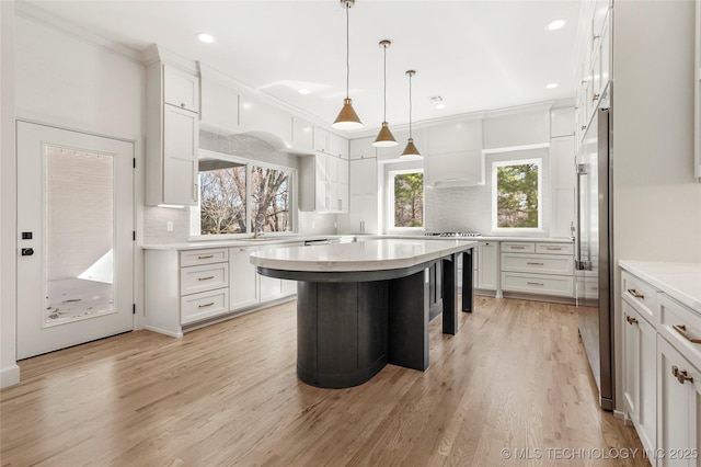 kitchen with decorative backsplash, white cabinets, light countertops, and light wood-style floors