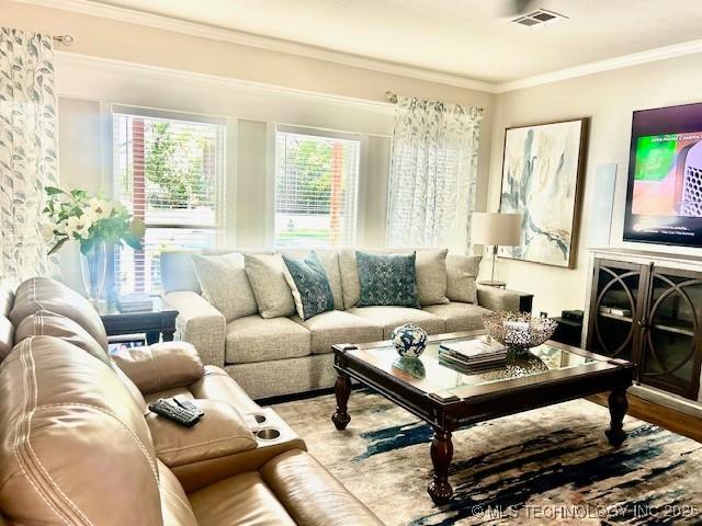 living area featuring visible vents, crown molding, and wood finished floors