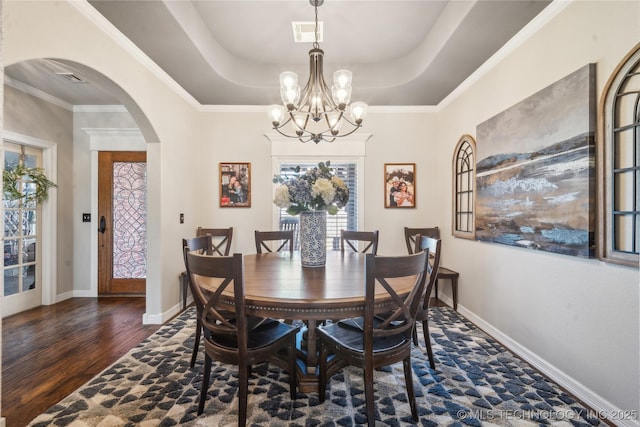 dining room featuring arched walkways, a raised ceiling, visible vents, wood finished floors, and baseboards