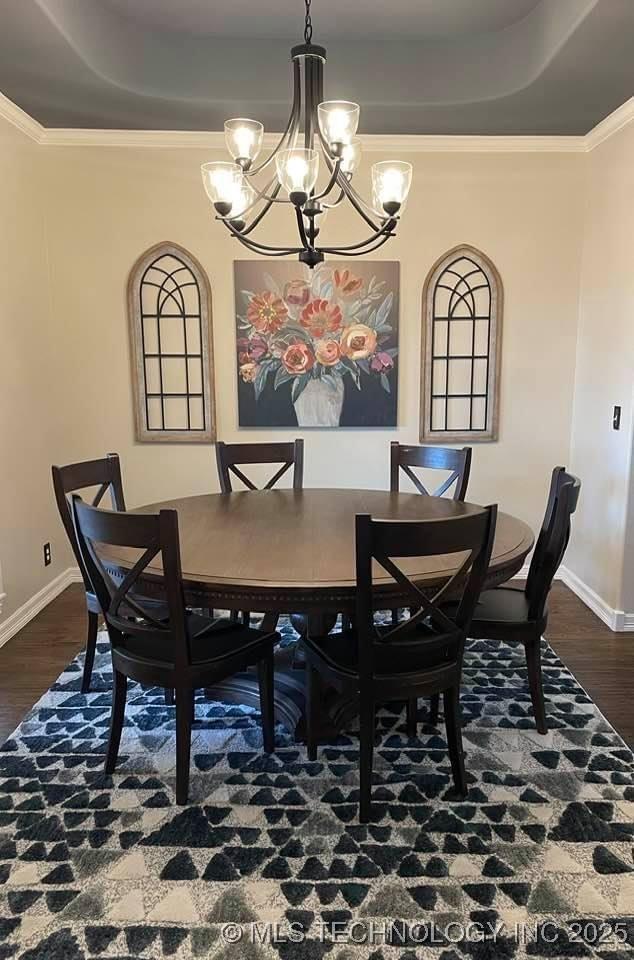 dining room with dark wood-style flooring, a raised ceiling, and baseboards