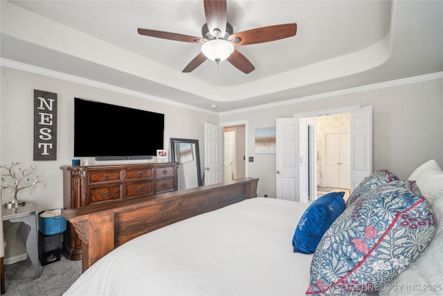 bedroom with a ceiling fan, a tray ceiling, carpet flooring, and ornamental molding