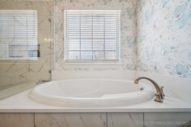 bathroom with a garden tub, a healthy amount of sunlight, and wallpapered walls