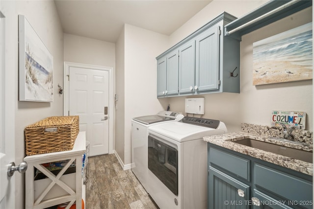 laundry room with light wood finished floors, washer and clothes dryer, a sink, and cabinet space