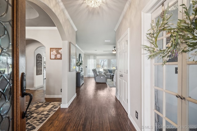 entrance foyer with dark wood-style floors, ornamental molding, arched walkways, baseboards, and ceiling fan