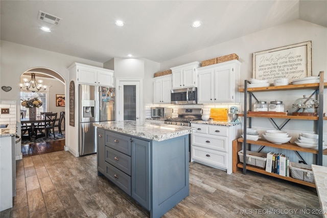 kitchen with white cabinets, visible vents, stainless steel appliances, and arched walkways