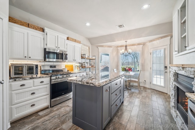 kitchen featuring gray cabinets, an inviting chandelier, stainless steel appliances, visible vents, and a kitchen island