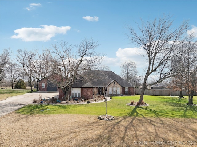 view of front of property featuring a front yard, brick siding, fence, and driveway