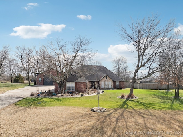 view of front of house with driveway, fence, a front yard, a garage, and brick siding