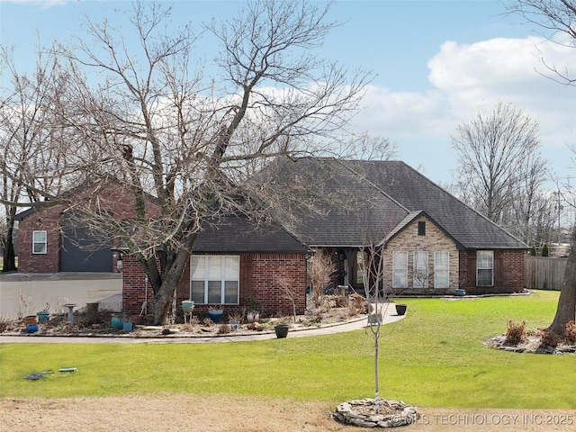 view of front of home featuring a shingled roof, a front yard, brick siding, and fence