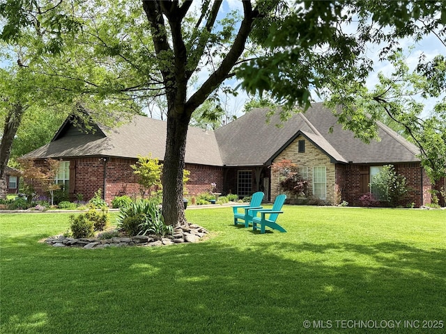 back of house featuring a lawn, a shingled roof, and brick siding