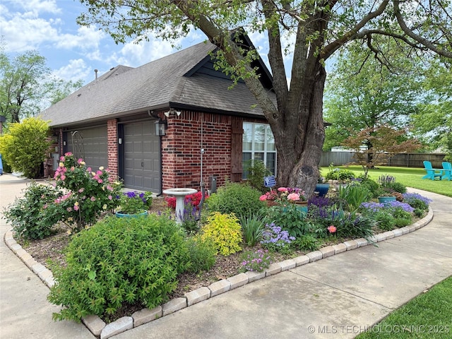 view of home's exterior with brick siding, an attached garage, roof with shingles, and fence
