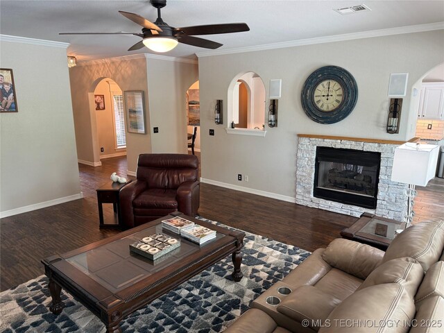 living area with wood finished floors, visible vents, ornamental molding, arched walkways, and ceiling fan