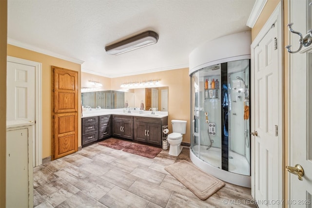 bathroom with toilet, a shower stall, vanity, and crown molding