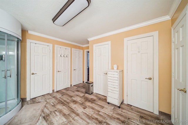 unfurnished bedroom with multiple closets, crown molding, and light wood finished floors