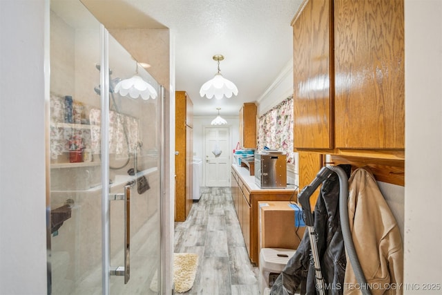 interior space with light wood-style floors, ornamental molding, brown cabinets, and decorative light fixtures