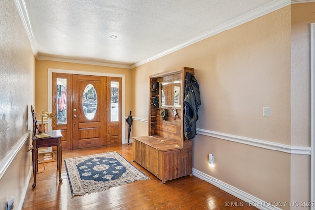 foyer entrance featuring baseboards, a textured wall, ornamental molding, wood finished floors, and a textured ceiling