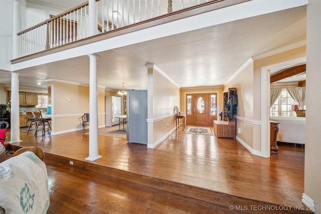 entryway with ornamental molding, hardwood / wood-style flooring, decorative columns, and baseboards