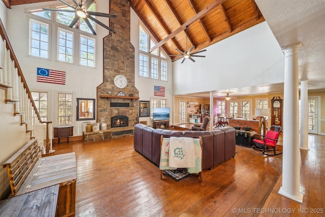 living area featuring ornate columns, hardwood / wood-style flooring, and a stone fireplace