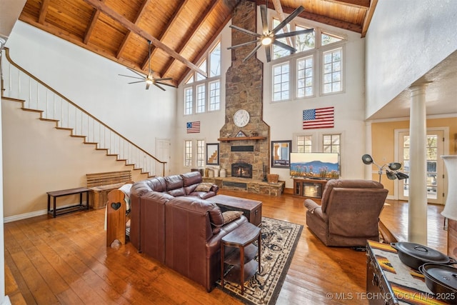 living area featuring ornate columns, wood ceiling, hardwood / wood-style flooring, and a stone fireplace