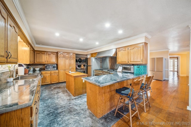 kitchen featuring a peninsula, a sink, appliances with stainless steel finishes, a center island, and tasteful backsplash