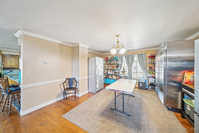 dining room with hardwood / wood-style floors, ornamental molding, a textured ceiling, a chandelier, and baseboards