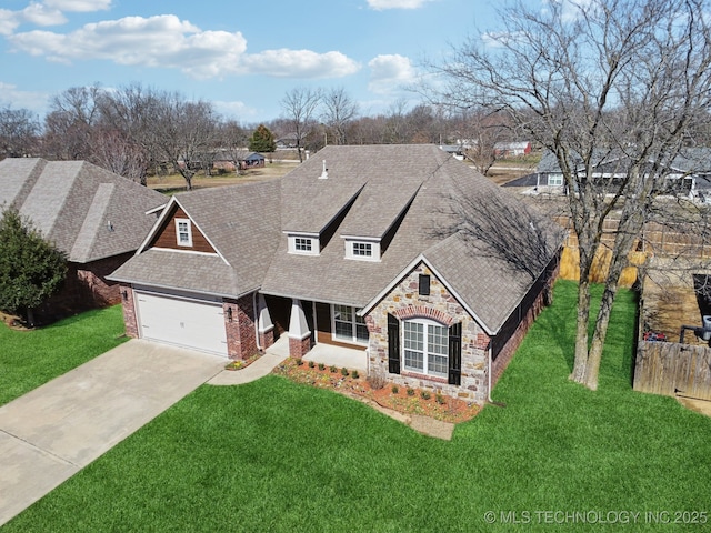 view of front of property featuring a front lawn, concrete driveway, stone siding, and roof with shingles