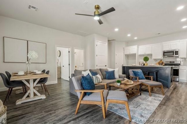 living room with baseboards, dark wood finished floors, visible vents, and recessed lighting