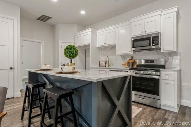 kitchen featuring tasteful backsplash, appliances with stainless steel finishes, visible vents, and white cabinets