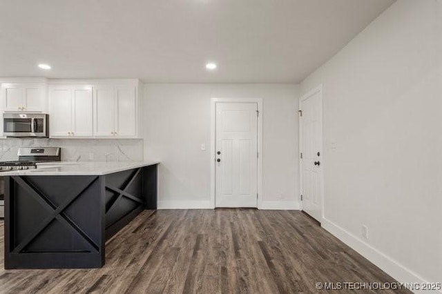 kitchen with dark wood-style floors, tasteful backsplash, appliances with stainless steel finishes, white cabinetry, and baseboards