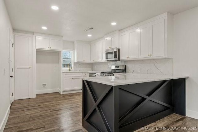 kitchen featuring a peninsula, visible vents, white cabinetry, appliances with stainless steel finishes, and dark wood-style floors