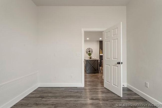 spare room featuring baseboards and dark wood finished floors