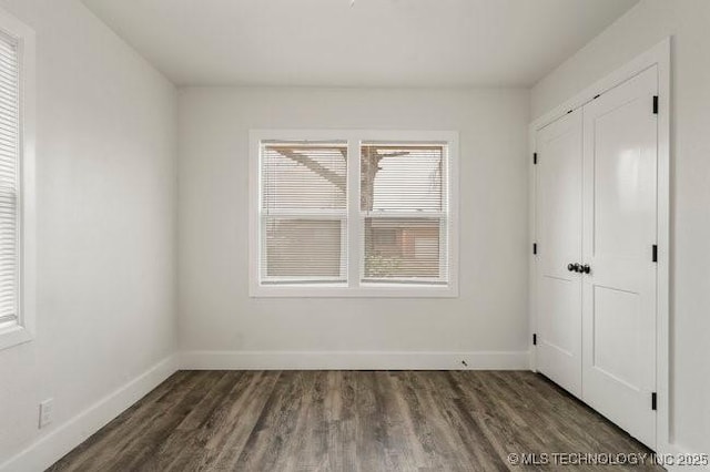 unfurnished bedroom featuring a closet, dark wood finished floors, and baseboards