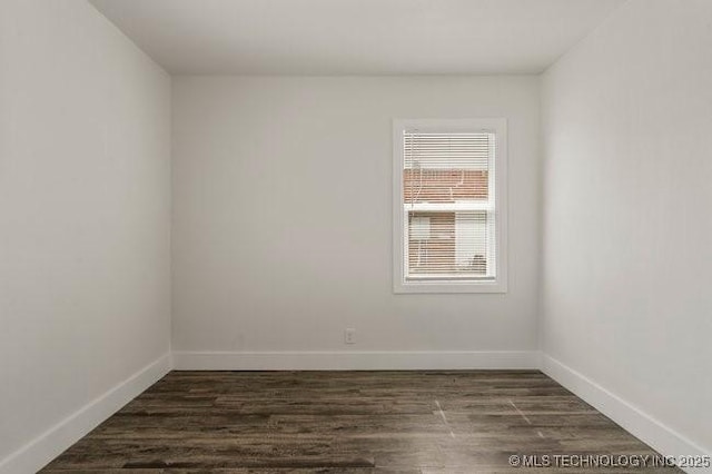 empty room with dark wood-type flooring and baseboards