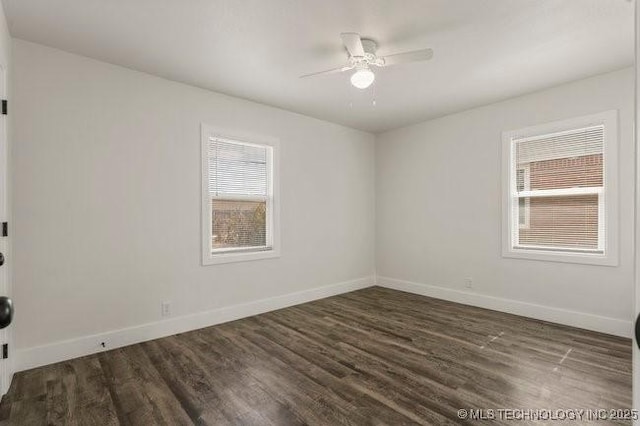 spare room featuring dark wood-style flooring, a ceiling fan, and baseboards