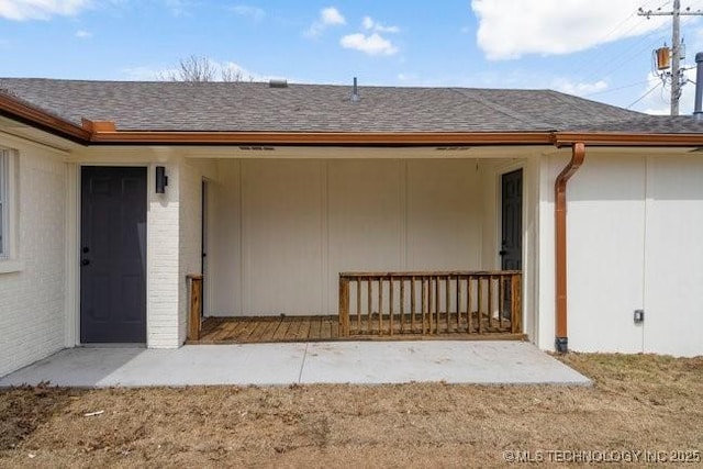 property entrance featuring brick siding and roof with shingles