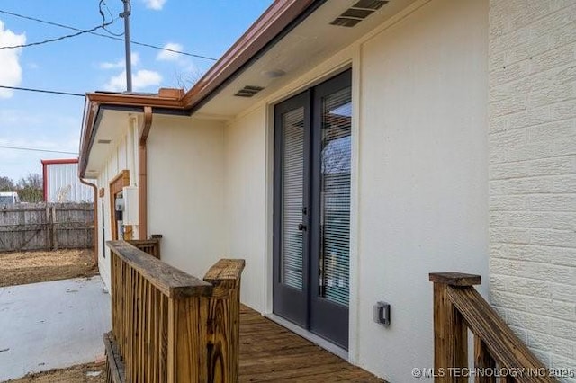 exterior space featuring visible vents, fence, and brick siding